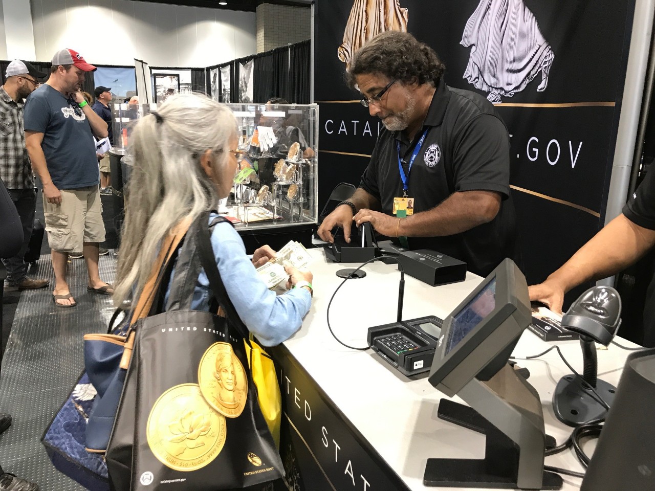 A customer makes a purchase from the U.S. Mint at booth #478.