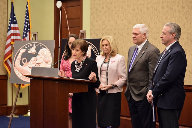 Woman standing at a podium with two women and two men standing behind her.