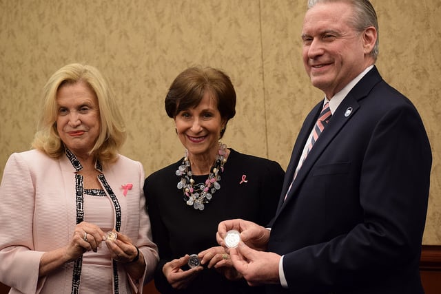 Two women and a man holding coins