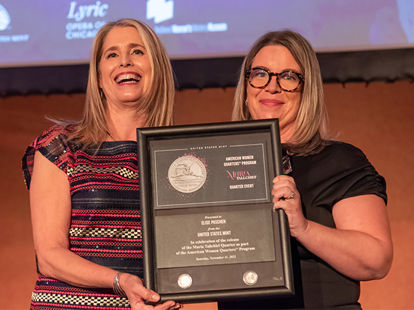 Deputy Director McNally and Elise Paschen hold a shadow box frame between them