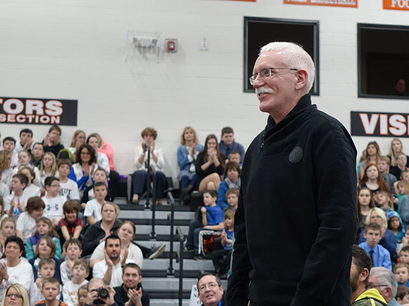 man standing in front of people sitting on bleachers
