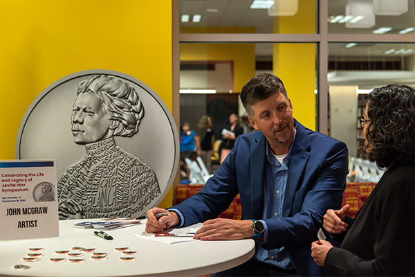 U.S. Mint Medallic Artist John McGraw talks to a woman