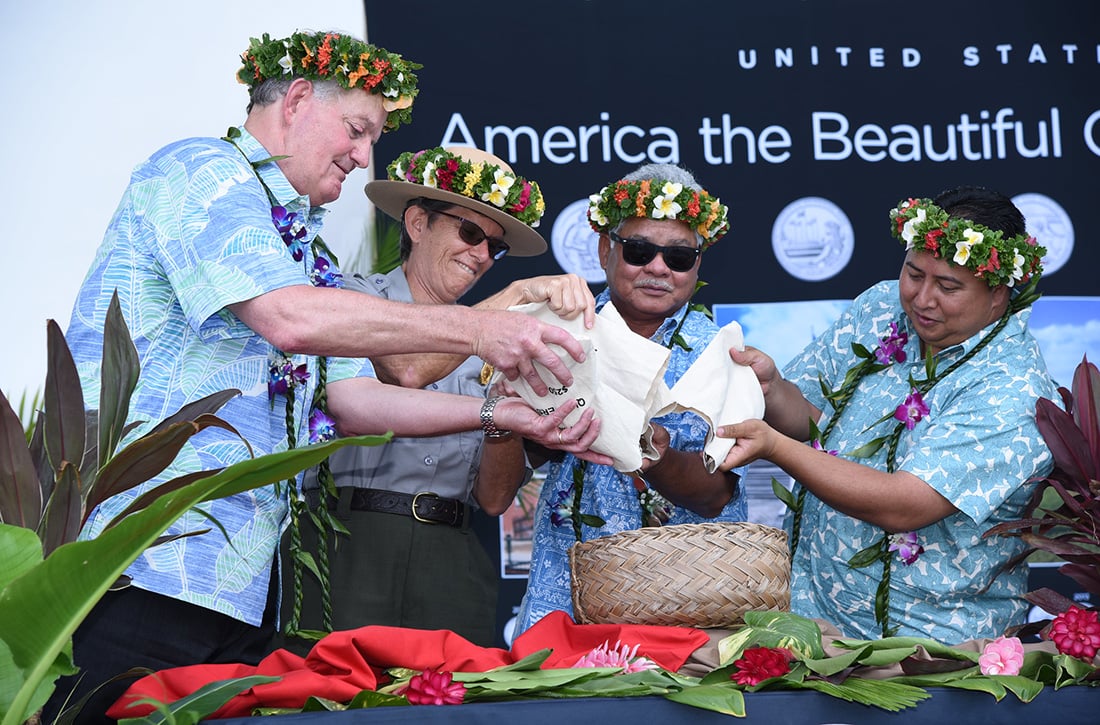 Director Ryder, Superintendent Barbara Alberti, Lieutenant Governor Arnold Palacios, and Governor Ralph Torres pour coins into a basket.