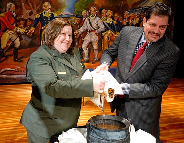 Superintendent Amy Bracewell and Acting Quality Manager Ron Harrigal pour new Saratoga National Park quarters into an old kettle