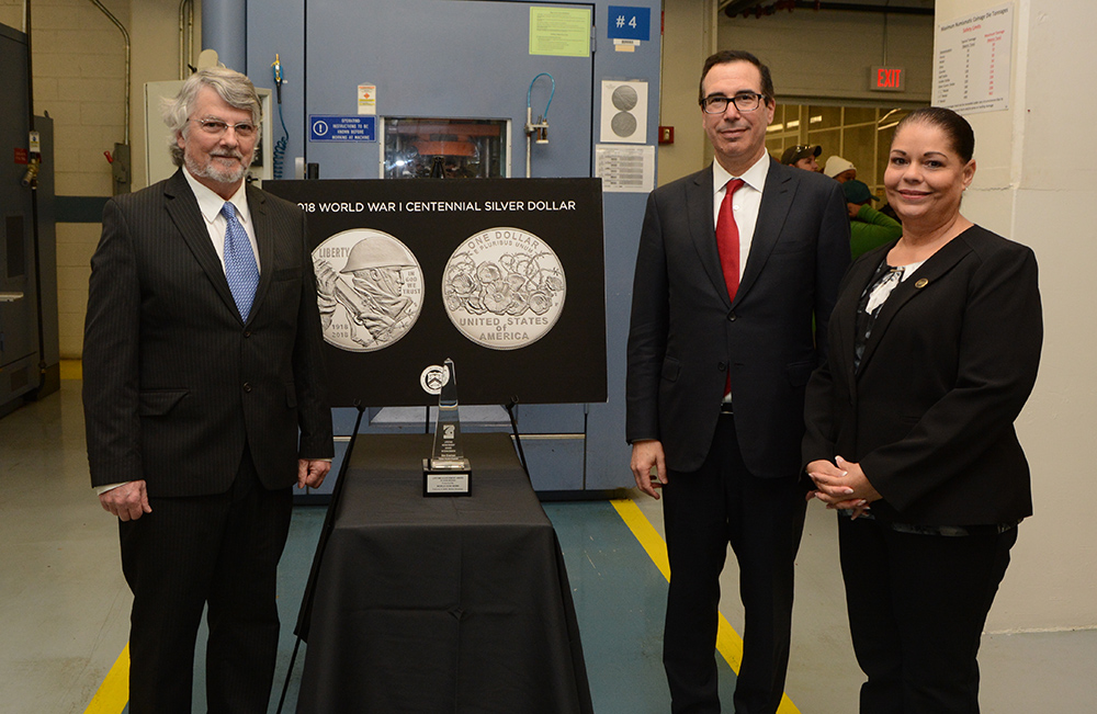 Don Everhart, Secretary Mnuchin, and Laurie Johnson stand by a table