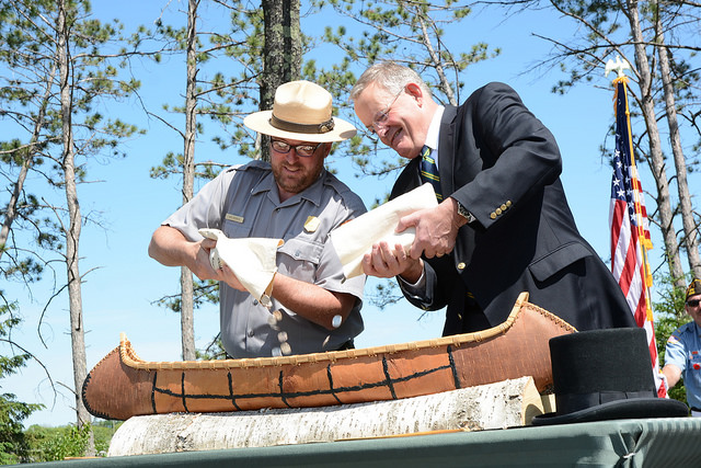 two men pour coins into a small canoe