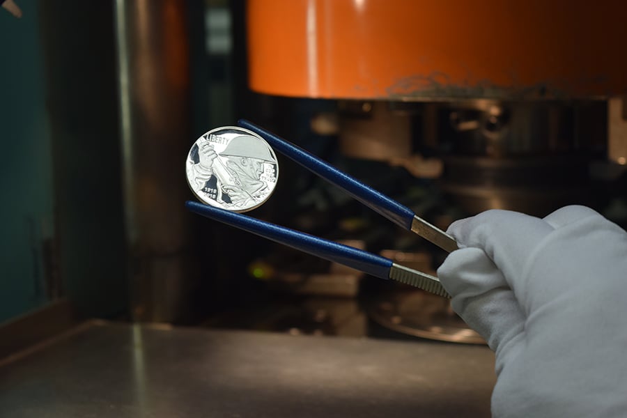 newly-minted World War I Centennial Silver Dollar held by tweezers