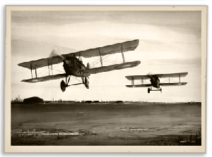 Two biplanes flying over a field