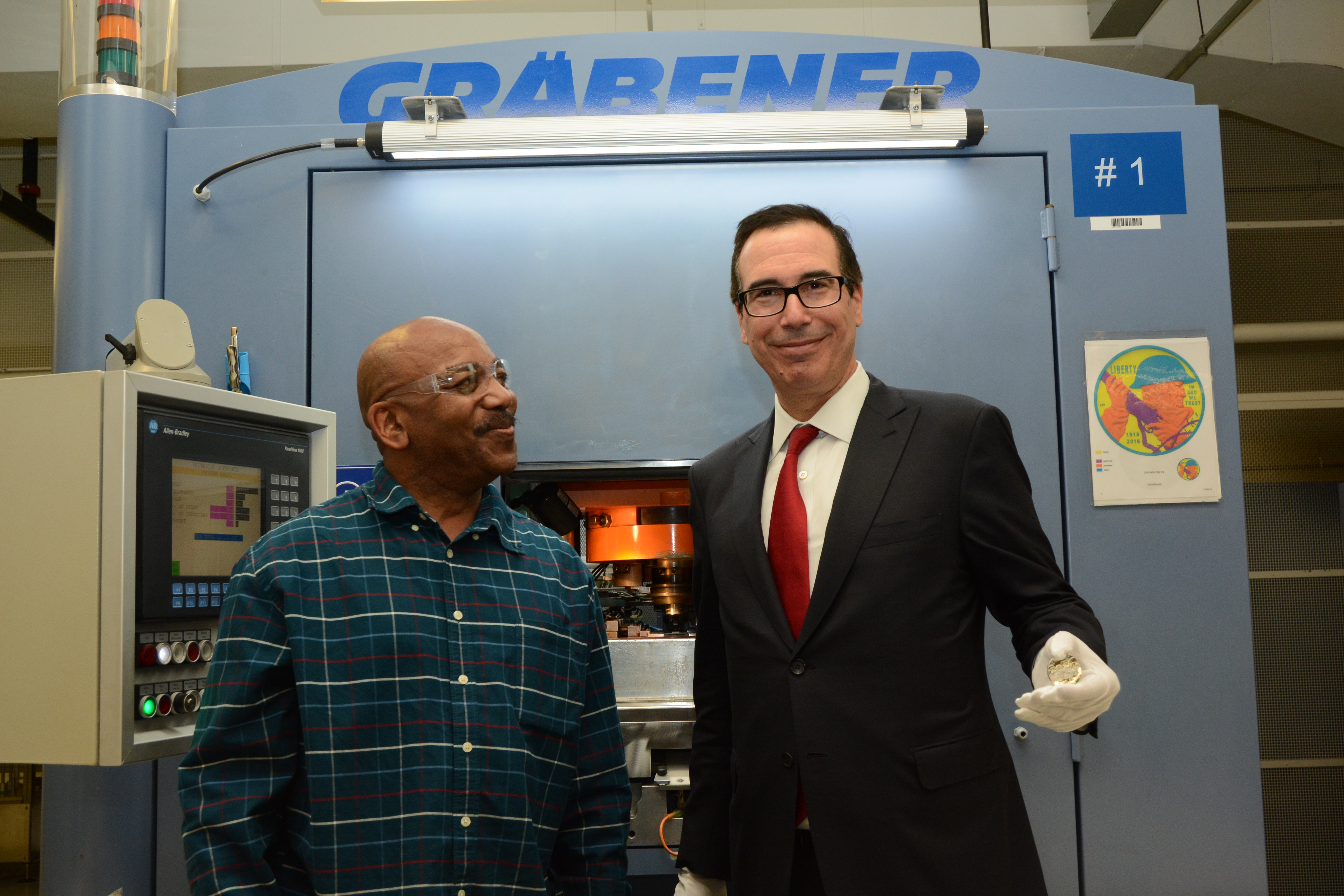 U.S. Mint Coin Press Operator Kenny Holland poses for a photo with Treasury Secretary Steven Mnuchin, who is holding a newly struck World War I Centennial 2018 Proof Silver Dollar at the U.S. Mint facility in Philadelphia on February 22, 2018. U.S. Mint p