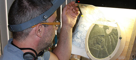 man sculpting a coin design