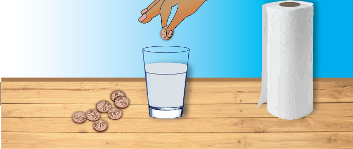 hand dropping a penny into glass of water with a piles of pennies and paper towels next to it