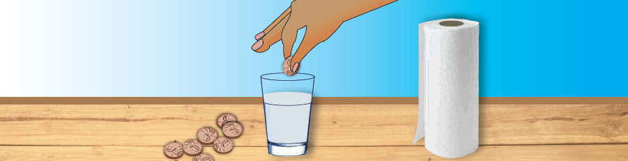 hand dropping a penny into glass of water with a piles of pennies and paper towels next to it