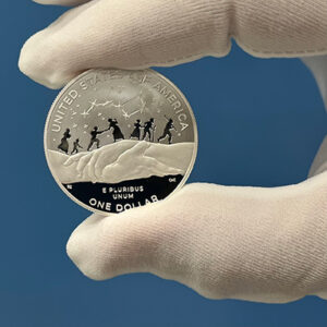 gloved hand holding a Harriet Tubman Silver Dollar Proof Coin